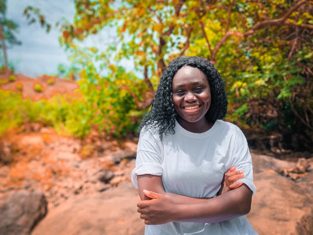 A woman smiling warmly outdoors in soft daylight